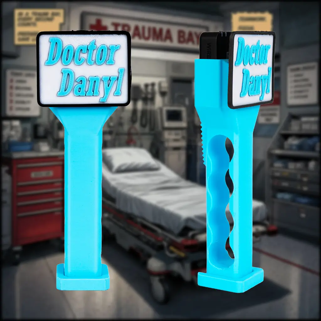 Image of a blue medium sized handle with a branding plate that reads, "Doctor Danyl". There is a slightly blurry background of an emergency room trauma bay.